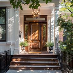 the front door of a house with stairs leading up to it and potted plants on either side