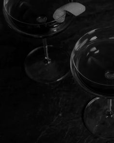 two empty wine glasses sitting next to each other on top of a black countertop