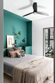 a bedroom with green walls and a bed in the middle, there is a fan on the ceiling