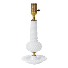 a white glass candle holder with a gold plated top and base, on a white background