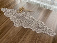 a white lace on a wooden floor with a small doll in the corner next to it