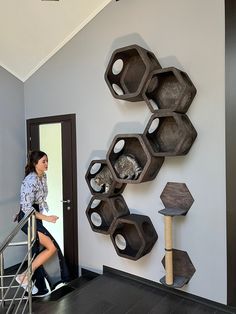 a woman sitting on a stair case next to a wall with hexagonal shelves