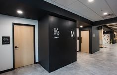 an empty room with black walls and wooden doors in front of the door is a sign that says m