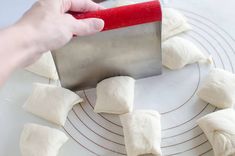 someone is using a red spatula to cut up dumplings on a white plate