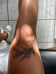 a woman's leg with an olive branch tattoo on her left side and foot