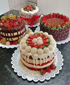 four cakes with strawberries and chocolate on top