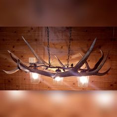 an antler lamp hanging from the ceiling with three lights on it and two deer heads