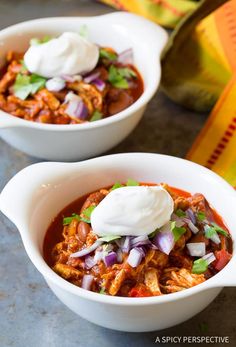 two white bowls filled with chili and sour cream