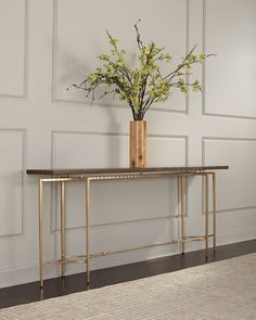 a vase filled with flowers sitting on top of a wooden table next to a wall