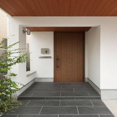 the entrance to a modern home with wood paneling and tile on the outside wall