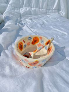 a bowl with two spoons in it sitting on a bed