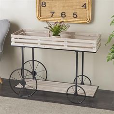 a wooden cart with wheels is sitting on the floor in front of a wall clock