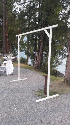 two white poles are in the middle of a gravel area next to some trees and water