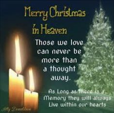 two lit candles are next to a christmas tree with the words merry christmas in heaven