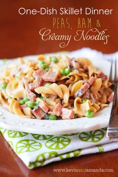 a bowl filled with pasta and ham on top of a green napkin next to a fork