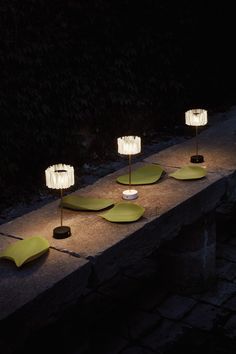 three lamps sitting on top of a stone slab in the dark, lit up by small lights