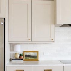 a kitchen with white cabinets and gold pulls on the cabinet doors is pictured in this image