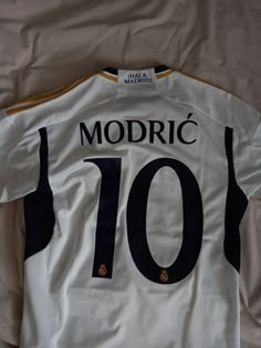 the jersey is white with black trim and has gold details on the chest, which reads modric's 10