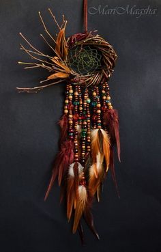 a dream catcher with feathers and beads hanging from it's side on a wall