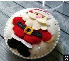 a santa clause ornament hanging from a string on a wooden table with wood planks