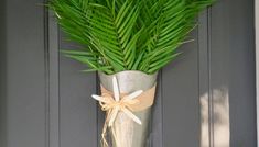 a plant in a metal vase on the front door with a ribbon tied around it