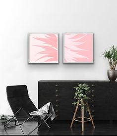 two pink paintings hang on the wall above a black dresser in a modern living room