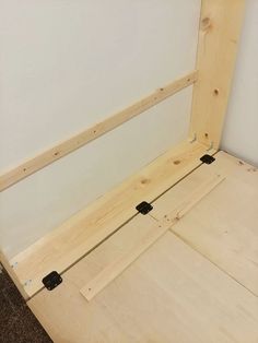 an unfinished bed frame sitting on top of a carpeted floor next to a wall