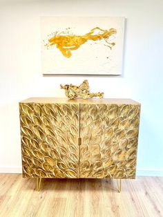 a gold leaf cabinet in front of a painting