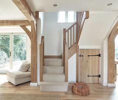 a living room filled with furniture next to a wooden stair case in front of a sliding glass door