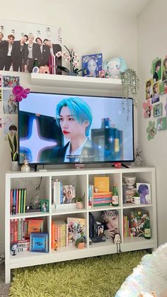 a flat screen tv sitting on top of a white book shelf next to a green rug