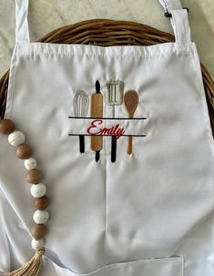 a white bag with an embroidered name on it and some kitchen utensils hanging from the handle