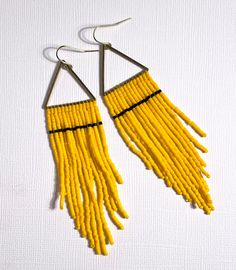 Such a lovely simple design. These pineapple yellow and black earrings are hand sewn with glass beads and thread on a brass triangle by our team of women in the Philippines working their way out of poverty. Materials - Brass, 14k gold hook, glass beads Measurements - 3”L x 3/4”W including hook Yellow Earrings With Gold Beads, Adjustable Yellow Earrings With Gold Beads, Adjustable Yellow Earrings With Tiny Beads, Yellow Adjustable Earrings With Tiny Beads, Yellow Seed Bead Earrings, Yellow Beaded Fringe Earrings, Yellow Handwoven Beaded Earrings For Festivals, Yellow Beaded Fringe Drop Earrings, Unique Yellow Beaded Earrings