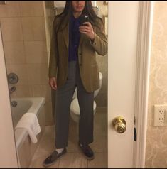 a woman taking a selfie in front of a bathroom mirror with her cell phone