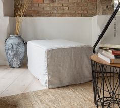 a small table with books and a vase on it next to a brick wall in a living room