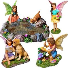 four fairy figurines sitting on top of a rock with flowers and plants around them