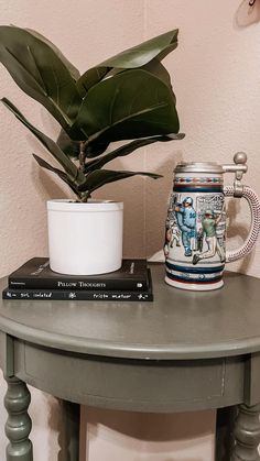 a green table with a mug and some books on it next to a potted plant