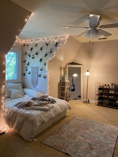 a bedroom decorated in white with fairy lights on the ceiling and bed spread over it