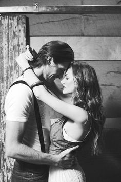 black and white photograph of a man and woman embracing in front of a wooden wall