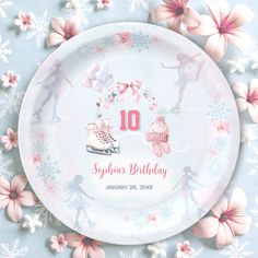 a paper plate decorated with ice skates and pink flowers on a blue tablecloth