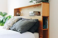 a bed that has some books on top of it and is next to a potted plant