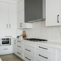 a kitchen with white cabinets and marble counter tops is pictured in this image, there are black handles on the cabinet doors