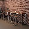 a row of bar stools in front of a brick wall