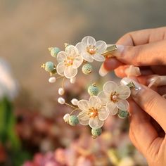 a person holding flowers in their hands with pearls on them and beads attached to the stems