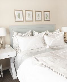 a bed with white sheets and pillows in a bedroom