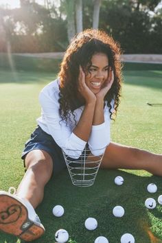 a woman is sitting on the grass with her feet up in front of golf balls