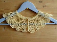 a crocheted shirt hanging on a wooden hanger