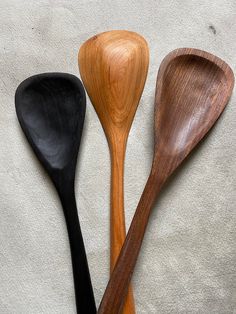 three wooden spoons sitting on top of a white countertop next to each other