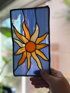 a hand holding up a stained glass sunflower