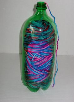 a bottle filled with yarn sitting on top of a white table next to a string