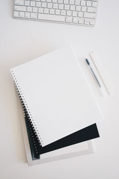 an open notebook sitting on top of a white desk next to a keyboard and mouse